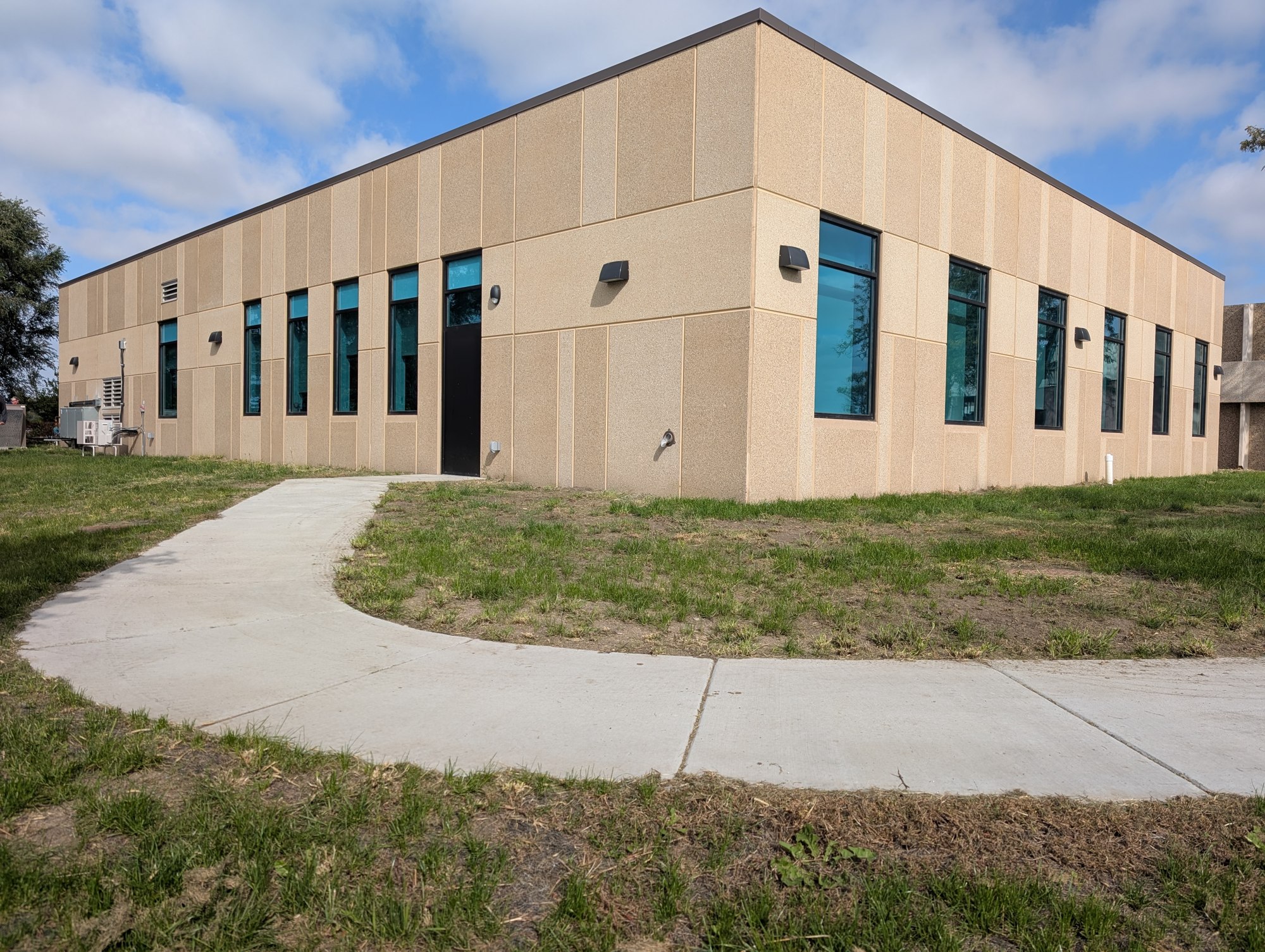 New Fort Thompson Health Center addition with tan exterior panels, tall windows, and a curved concrete walkway